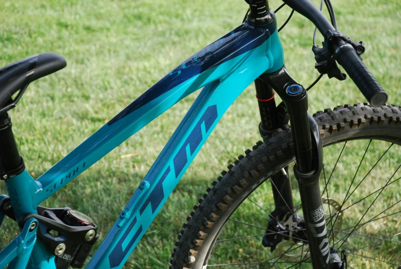 the blue and black bicycle is sitting in the grass