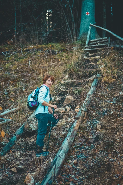 a woman walking down a rocky trail in the woods