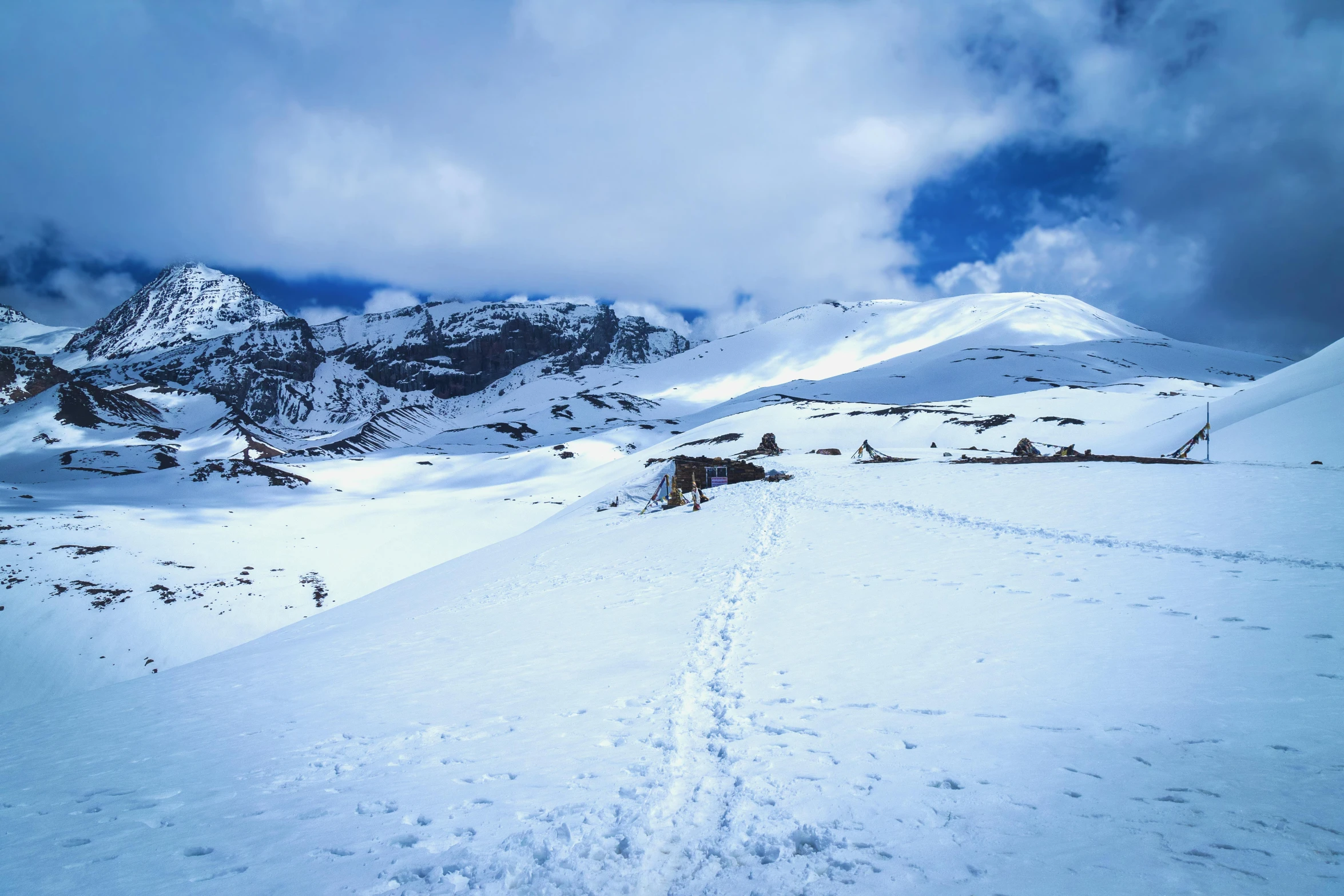 a trail splits through the snow towards some mountains