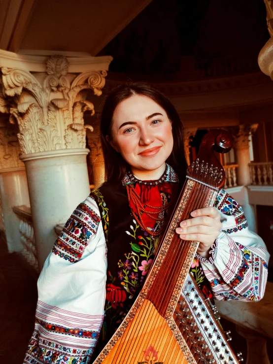 a woman holding an ornate instrument with a decorative motif