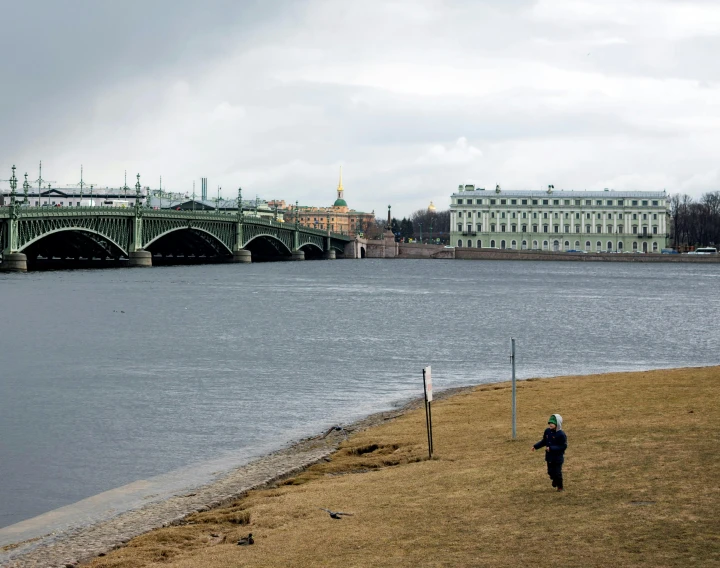 a person walks across a field next to the water