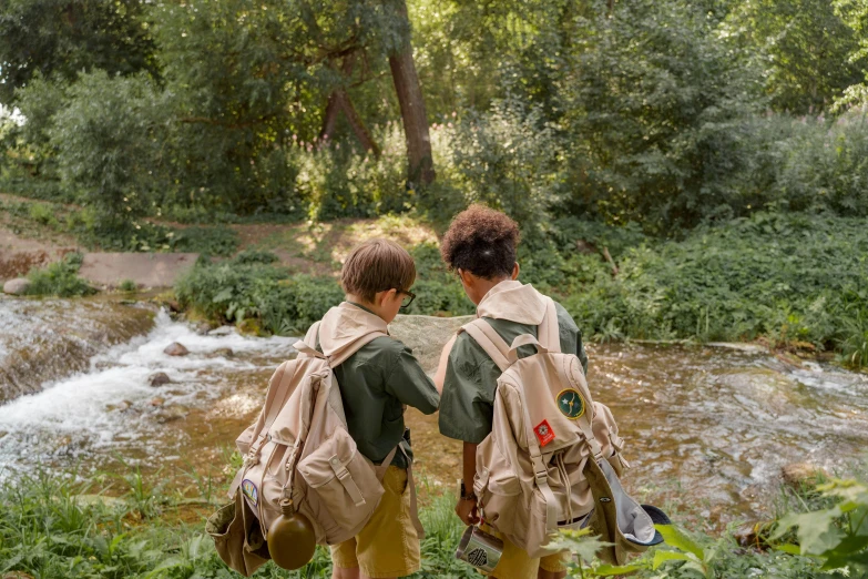 two s are walking through a forest, and are wearing backpacks