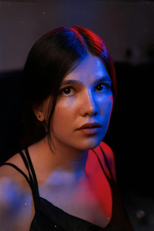 young woman with dark skin and red hair wearing black tank top looking off to the side