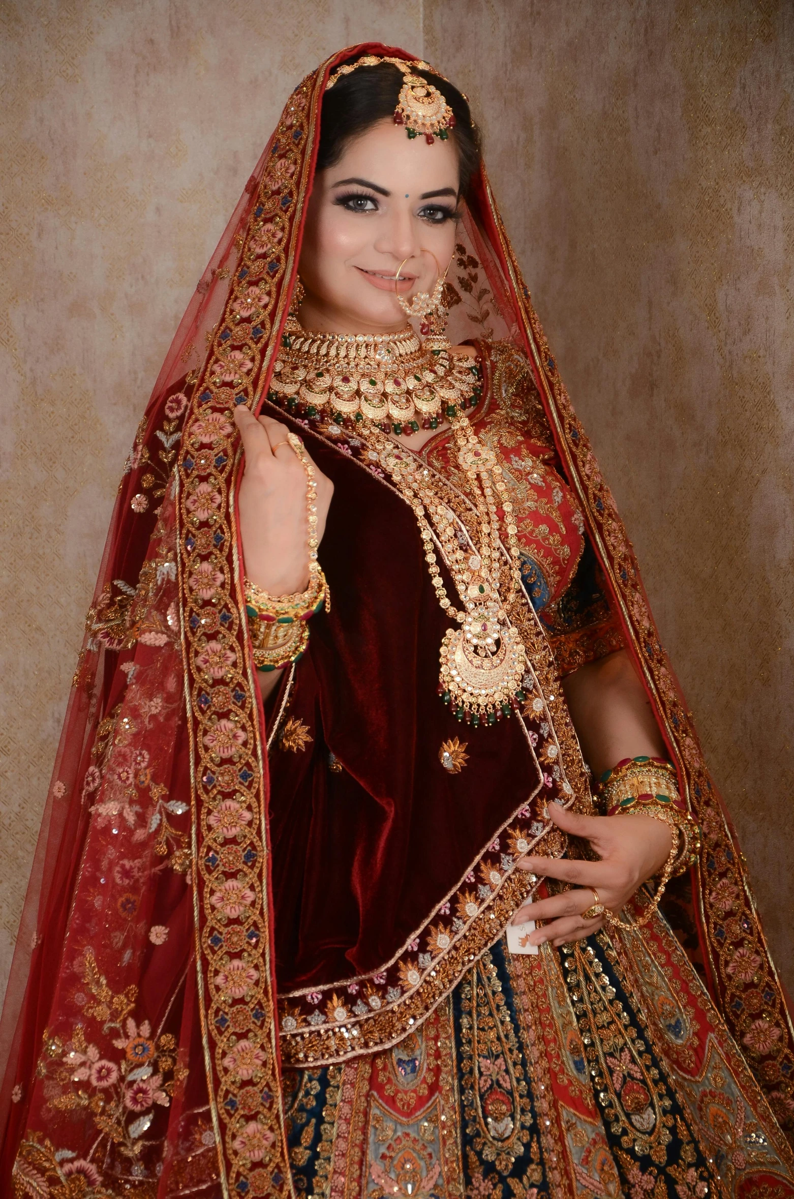 an indian bride wearing a red dress and gold jewelry