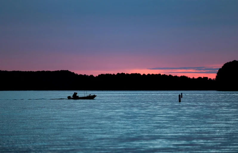 a couple fishing on the water at sunset