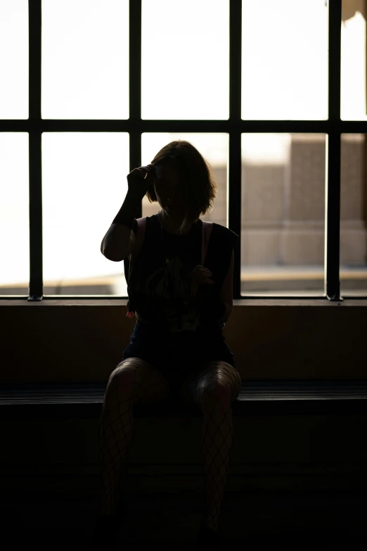 a person sitting on a bench by windows