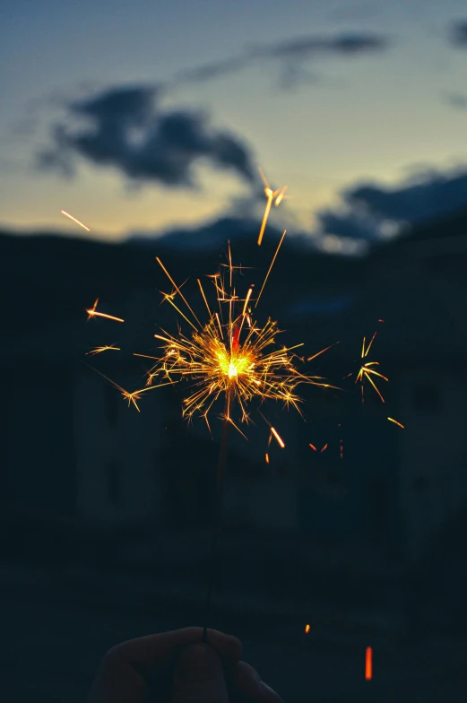 a person holds a lit sparkler in the dark