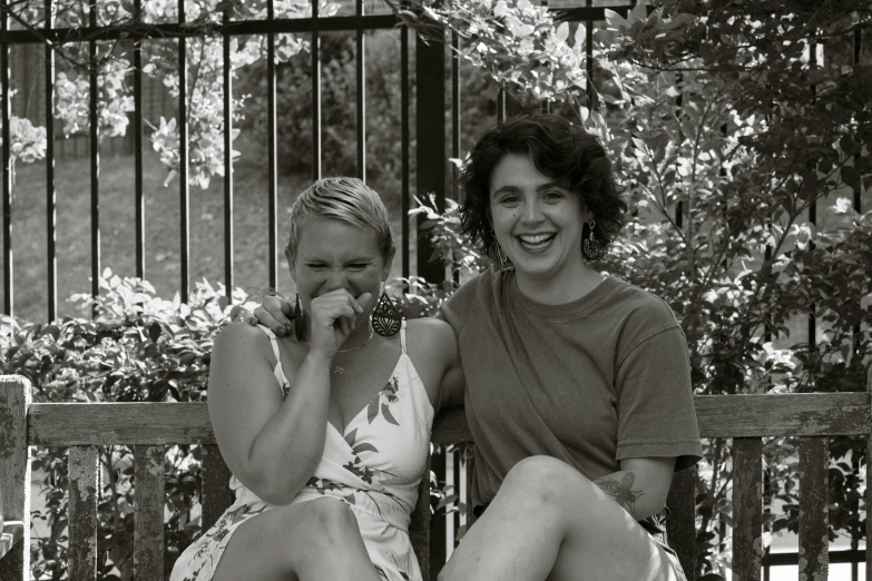 two beautiful women sitting next to each other on a bench