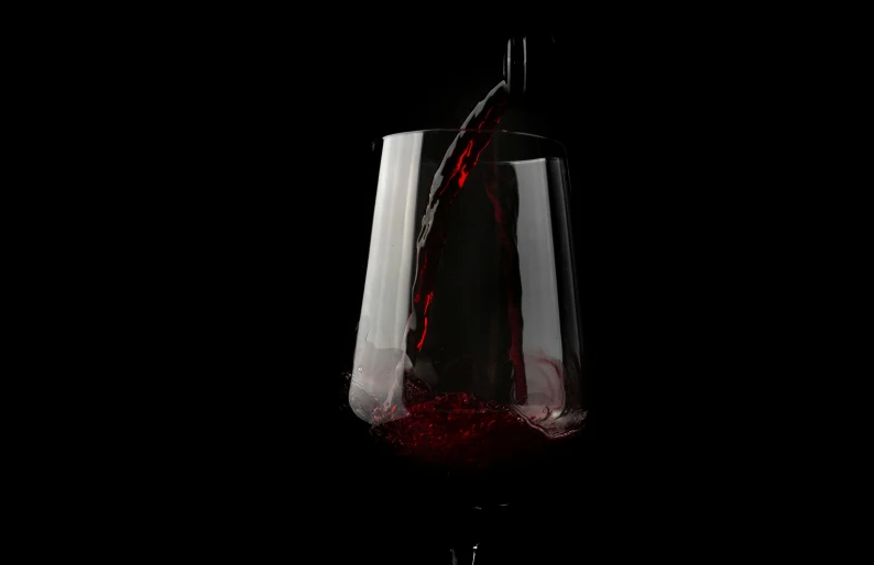 a wine glass is being filled with red liquid