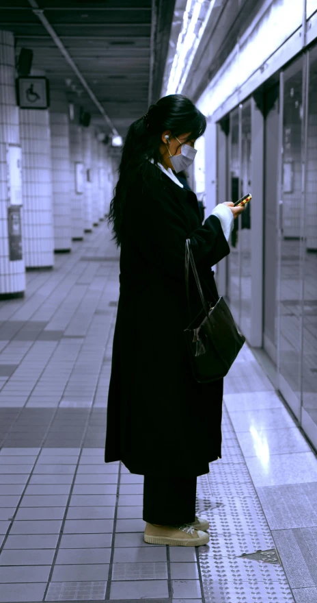 the woman with long hair wearing a mask is looking at her cellphone