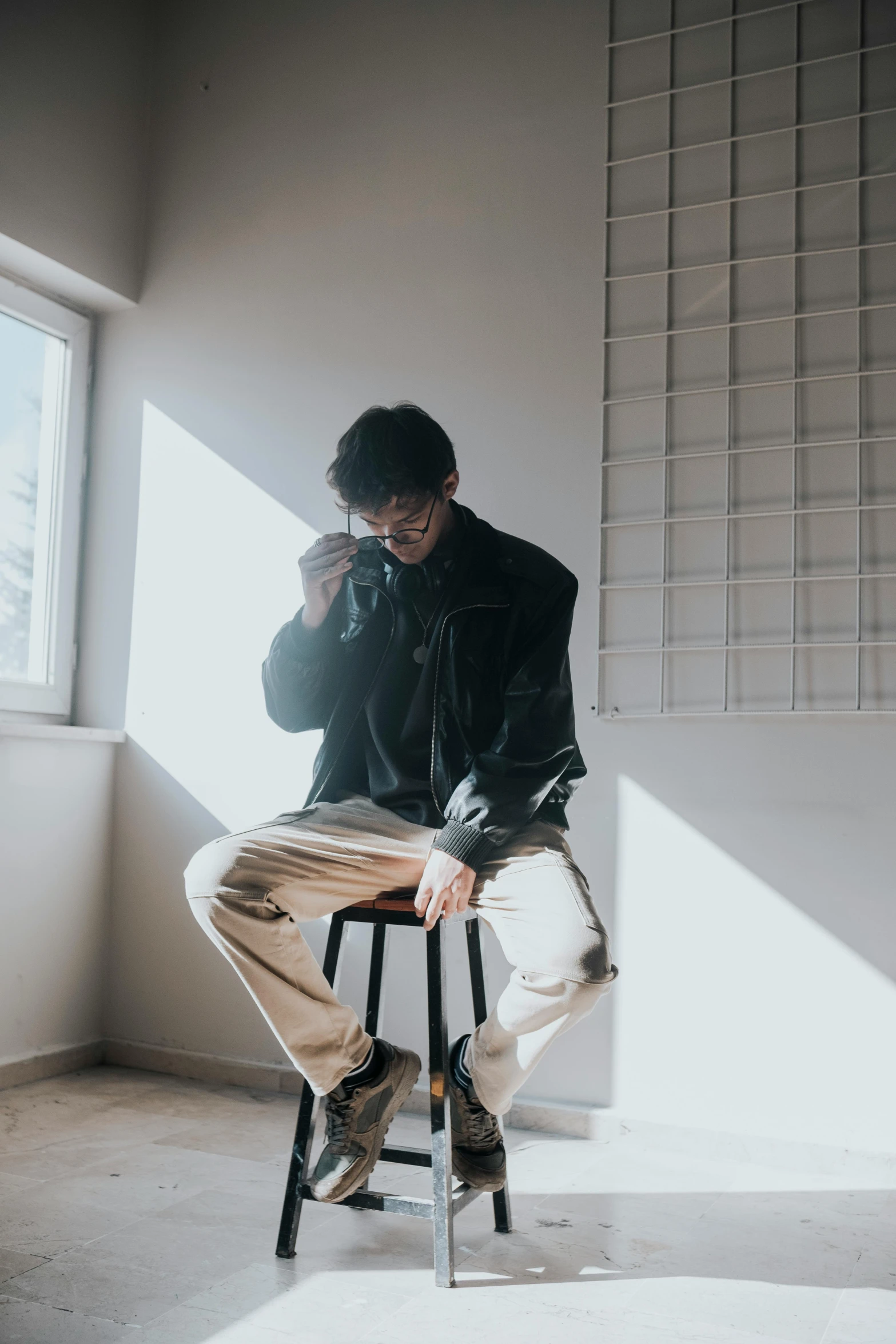 a man leaning on a stool with his arms folded as he talks on the phone