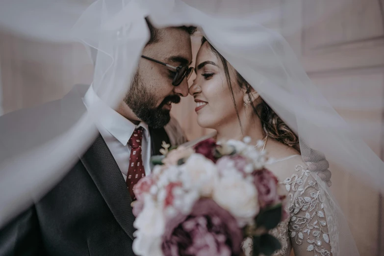 bride and groom under a veil during wedding pos