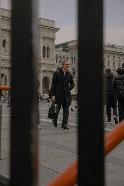 a man walking past a building with lots of people