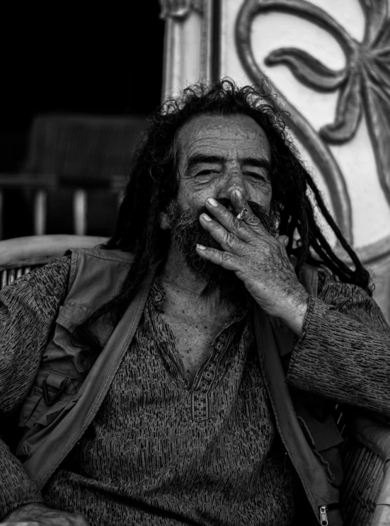 a man with dread locks on his face is holding a cigarette