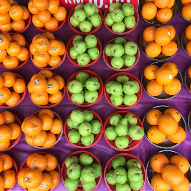 this fruit stand has oranges, apples and plums in baskets