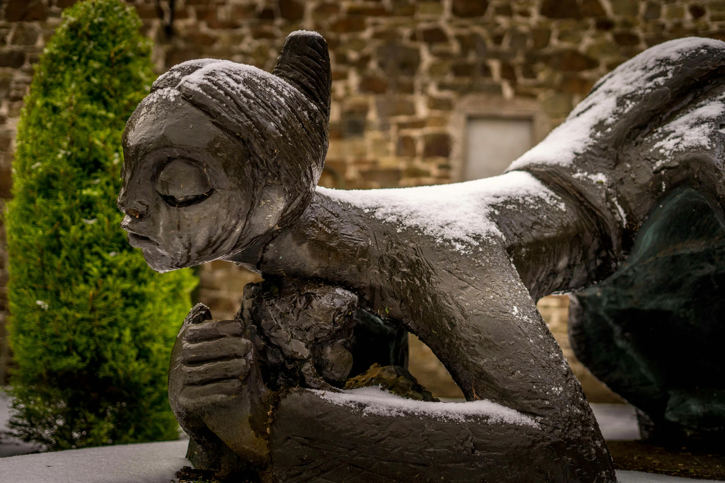 a statue in the snow by a wall