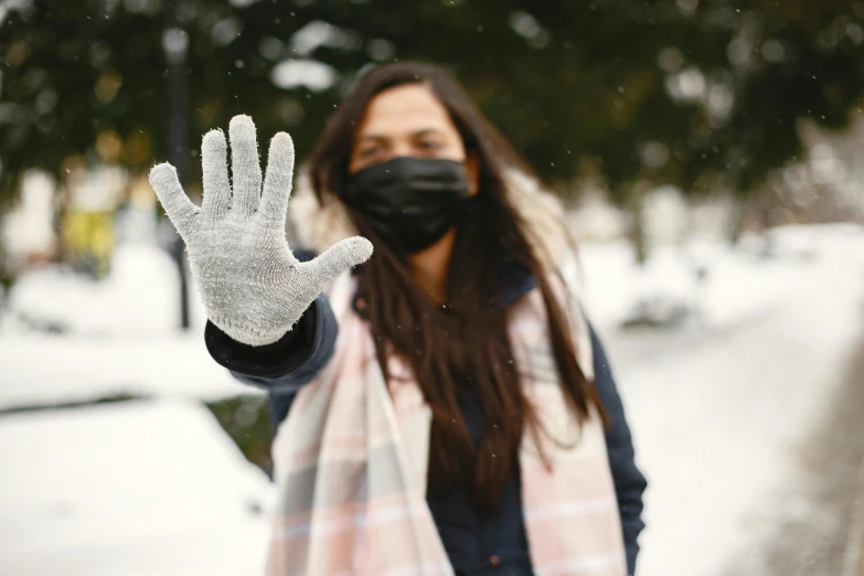 the person wearing a face mask is making an obscene gesture