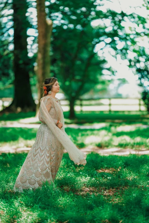 the bride in her gown is sitting down on grass and trees
