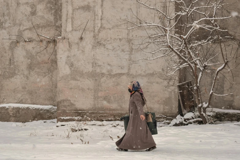 a woman walking in the snow with a back pack