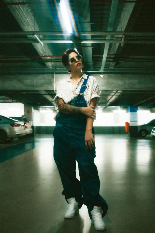 a woman in overalls and an apron standing under a metal bridge