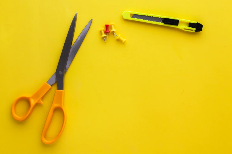 two pairs of yellow scissors and some other objects