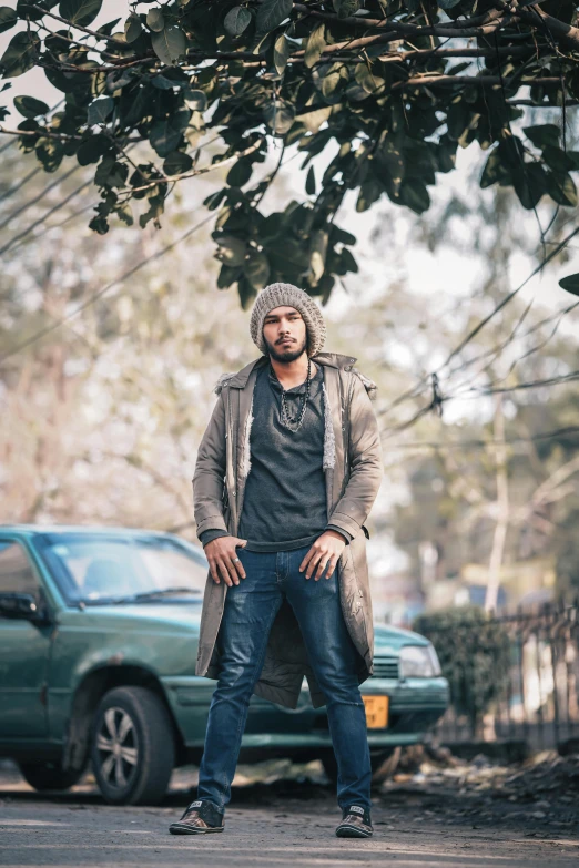 a man stands on a street corner while wearing a hat