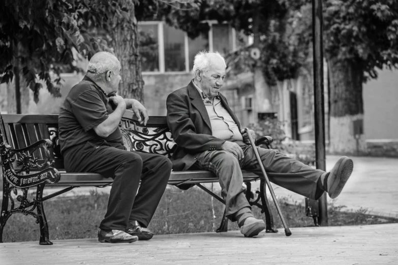 the older men are sitting on the bench together