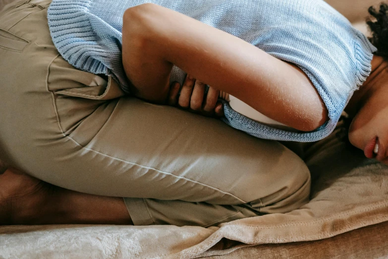 a woman in blue sweater laying on top of a bed