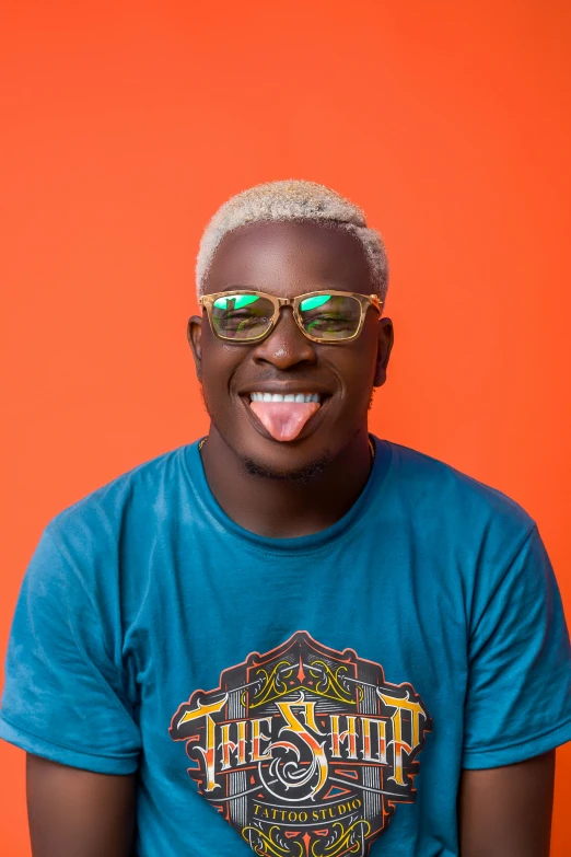 a man with sunglasses on and a blue shirt with an orange background