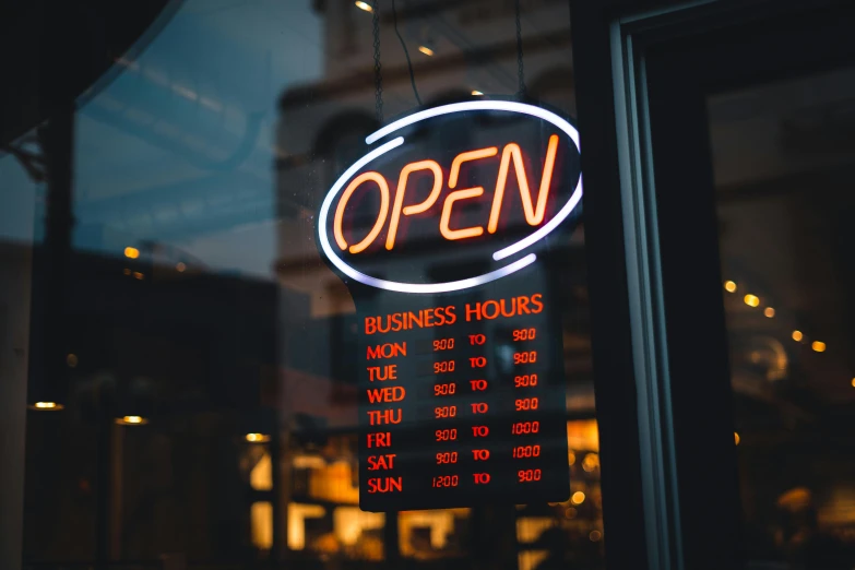 sign that says open with business hours displayed outside