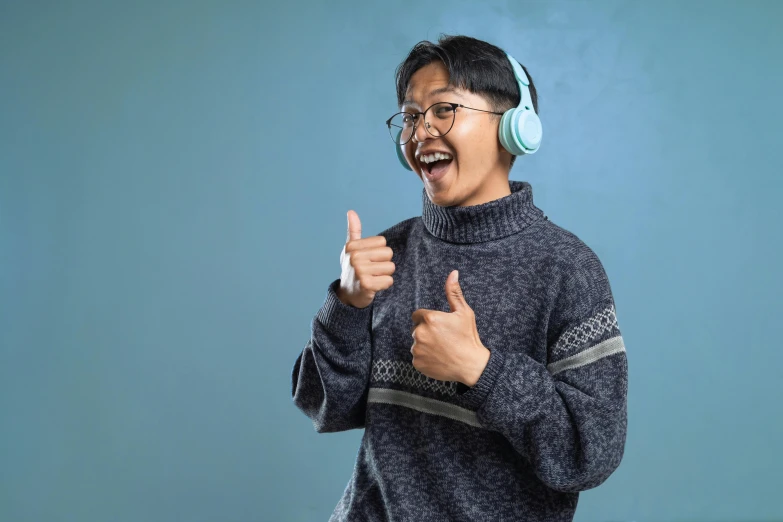 an asian man is wearing headphones and giving a thumbs up