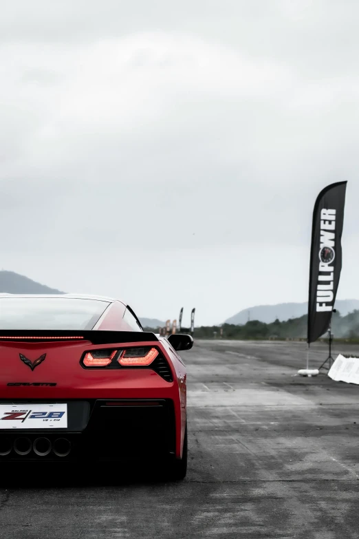 the red sports car is parked near a flag