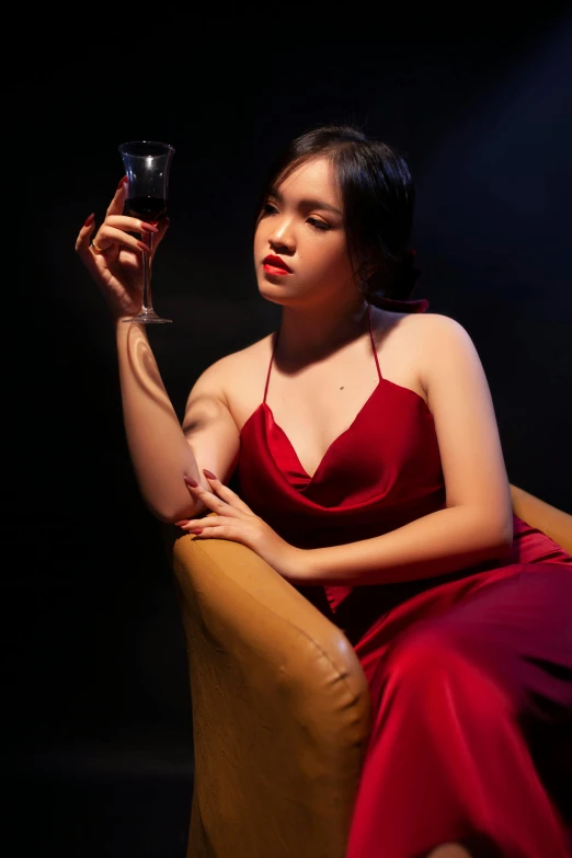 a woman in a dress sitting in a chair with a glass of wine