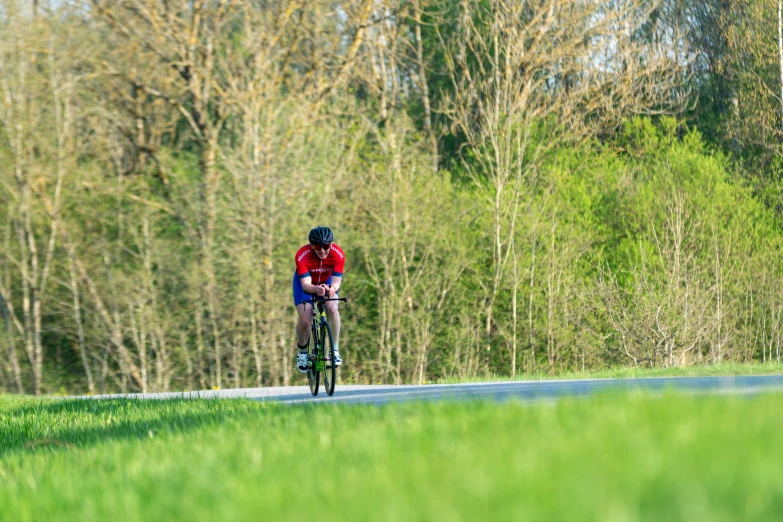 a man is biking down a grass covered road