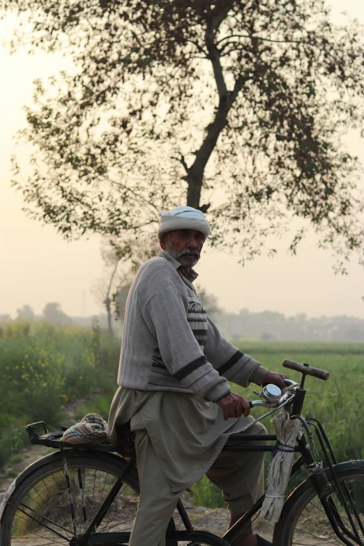 a man riding on a bicycle down a dirt road