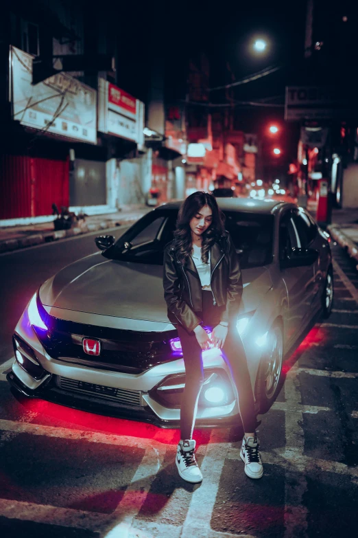 a woman sitting on a car posing for a po