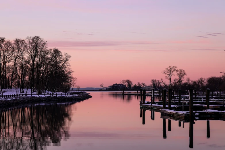 a pink sky and lake covered in snow