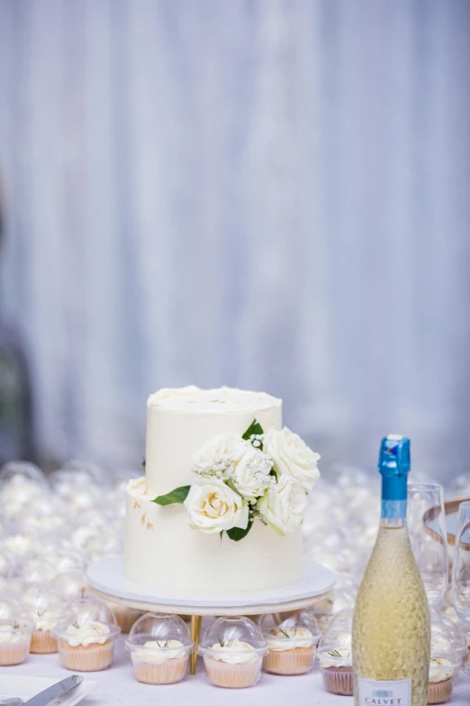 a white cake with flowers on the top and a bottle of wine next to it