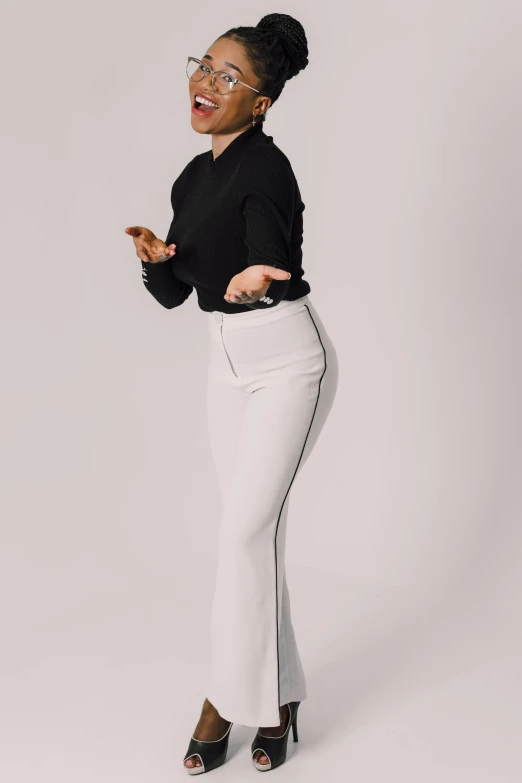 a black woman in white pants and black top pointing