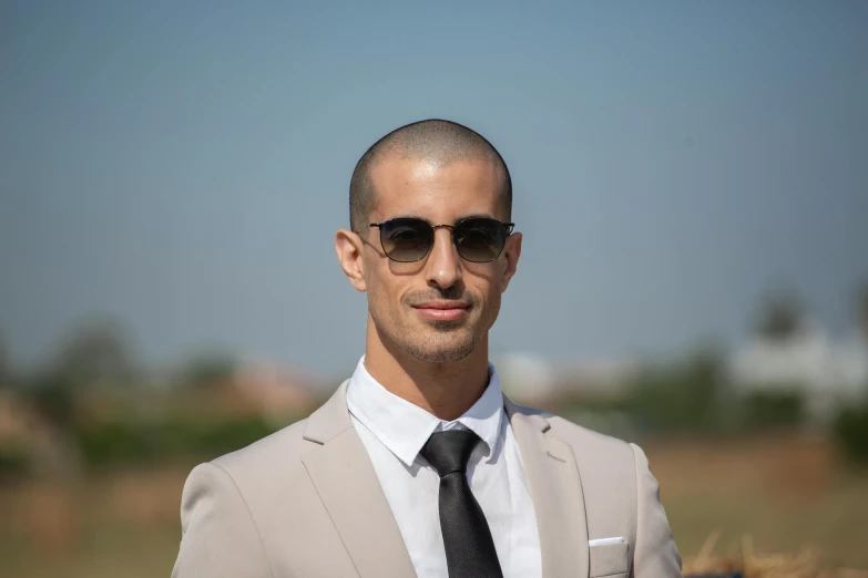 a man with sunglasses and a tie standing in a field