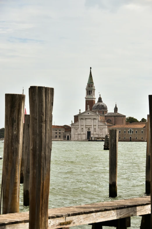 a bridge with wooden poles and an old building in the background