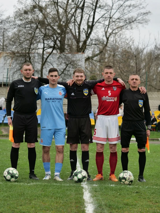 five men in uniforms stand with their arms around each other