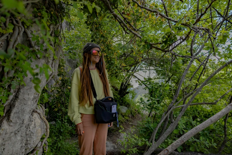 a man with long hair carrying a backpack in a tree filled area