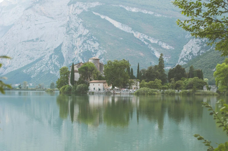 a small island in the middle of a lake with water and trees around