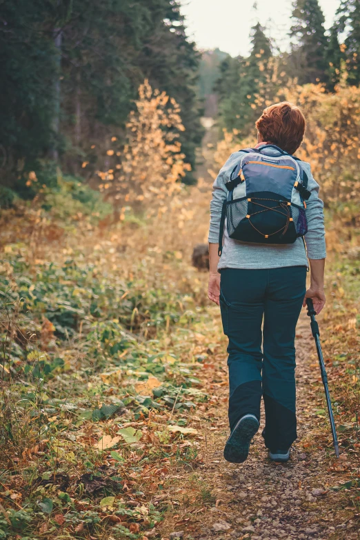 a woman hiking through the woods with a backpack