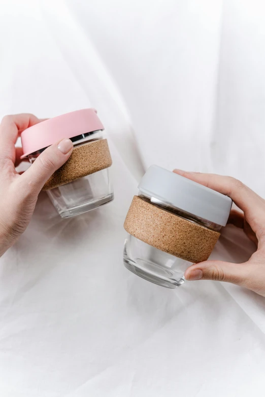 two small jars are holding lids in each hand