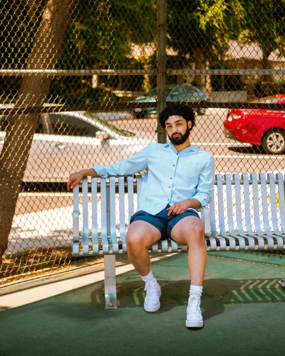 a man sitting on a bench by a fence