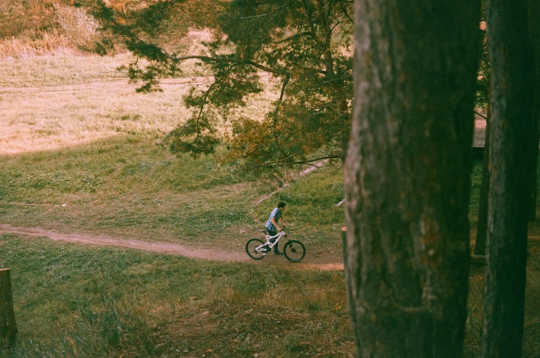 an aerial view of a man on a bike riding on the dirt trail near trees