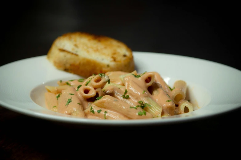 a plate of pasta with cream sauce and bread