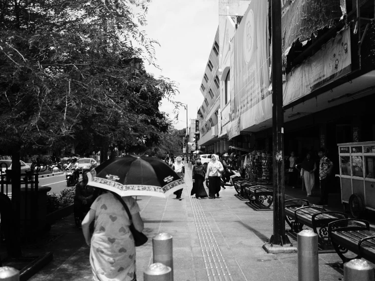 a woman with an umbrella is standing on a busy street